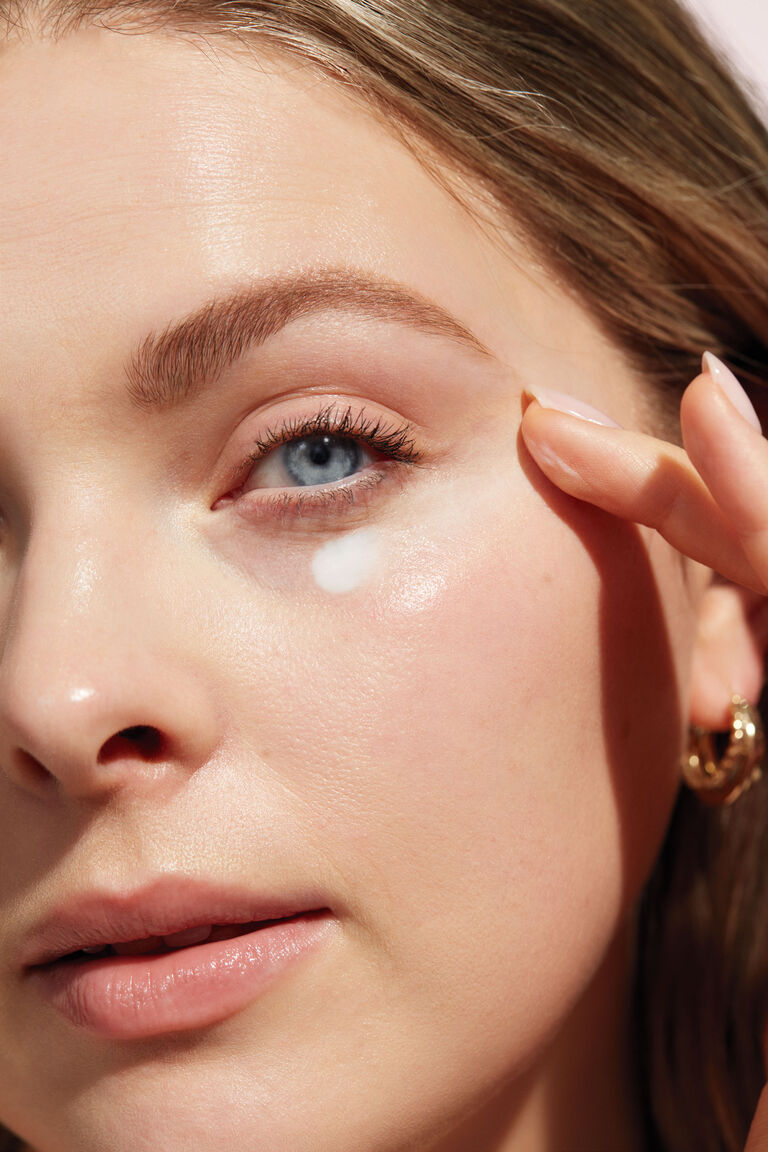 Close-up of a woman&rsquo;s face applying Mary Kay eye cream with her fingers.