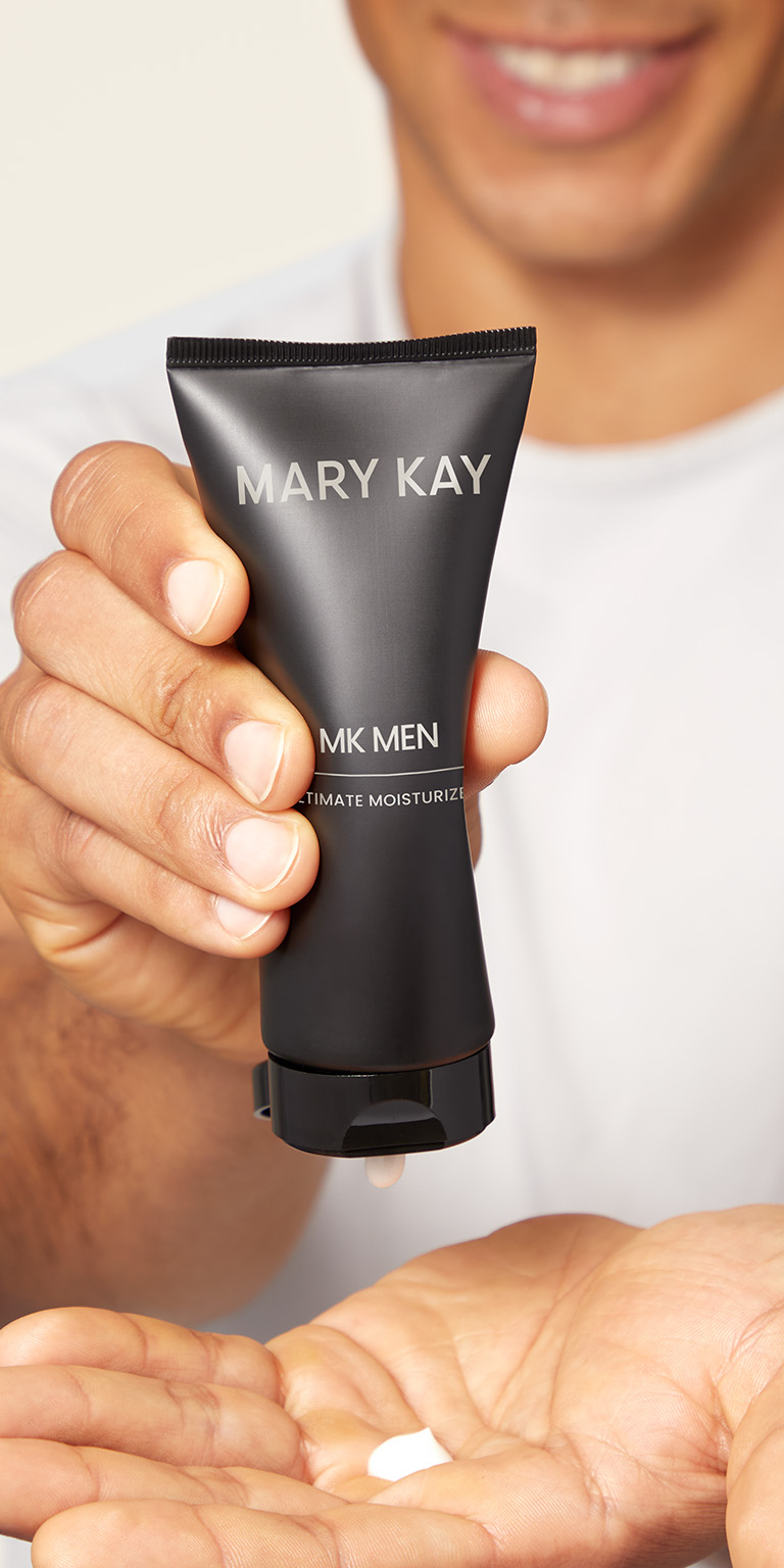 Male model squeezing MK Mens moisturizer into his hand